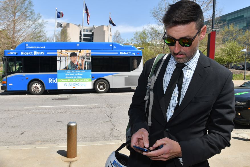 Kansas City Council member Eric Bunch scrolls through the Ride KC Transit app outside City Hall.